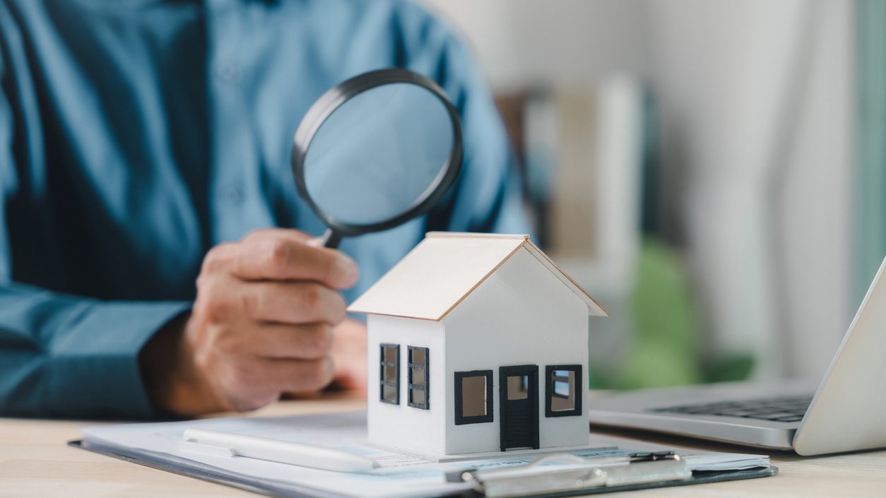 house model with man holding magnifying glass home inspection or searching for a house