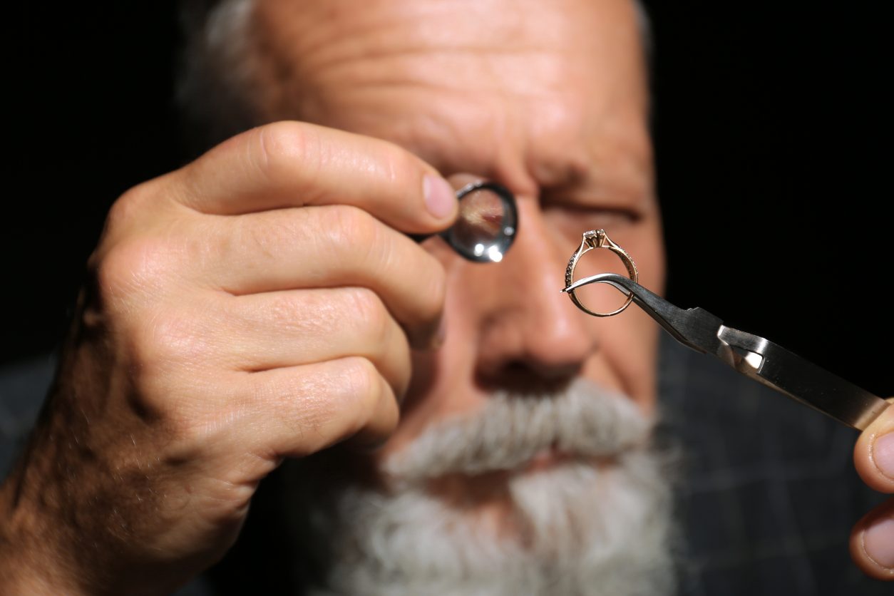 professional jeweler working with ring on dark background, closeup