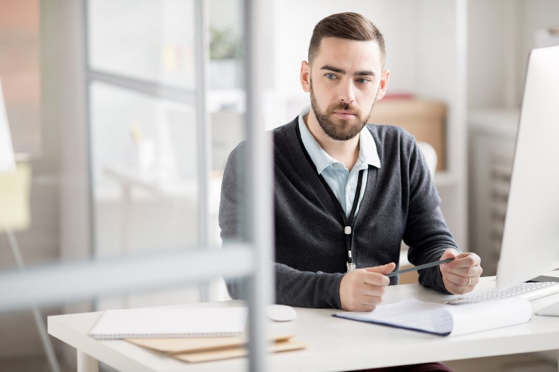 Man sitting behind desk thinking