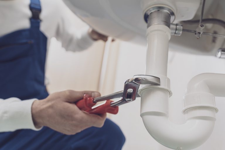 Plumber fixing white sink pipe