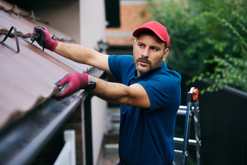 Man inspecting the gutters on a roof