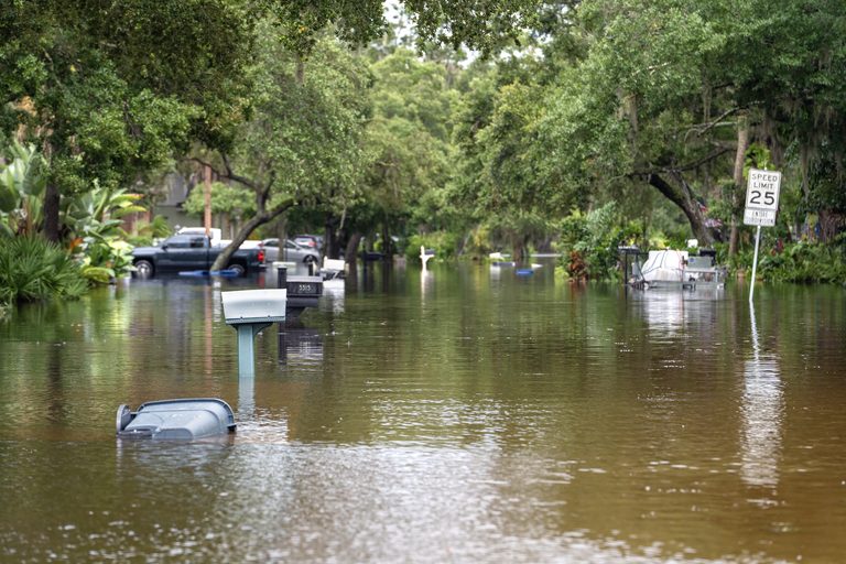 Flood water reaching half the height of a home's fence.