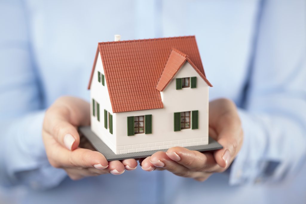 close up of hands holding house or home model
