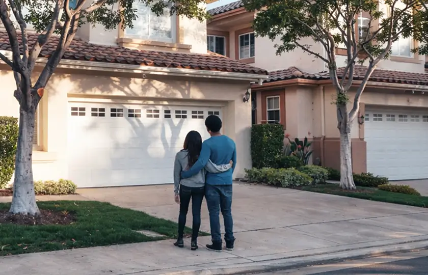 happy homeowners staring at their home horizontal shott