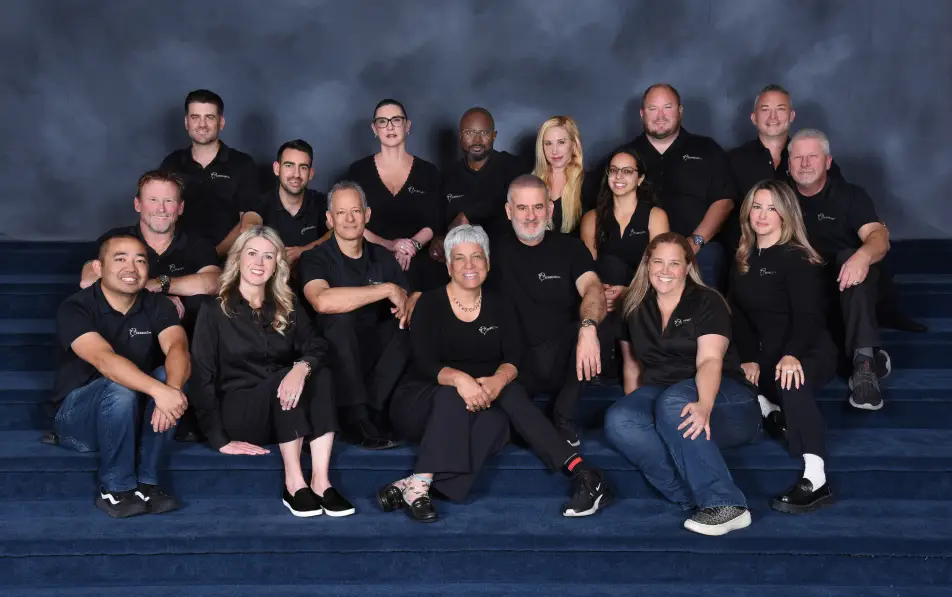 Portrait of the Avner Gat team wearing matching black company shirts, sitting on the stairs